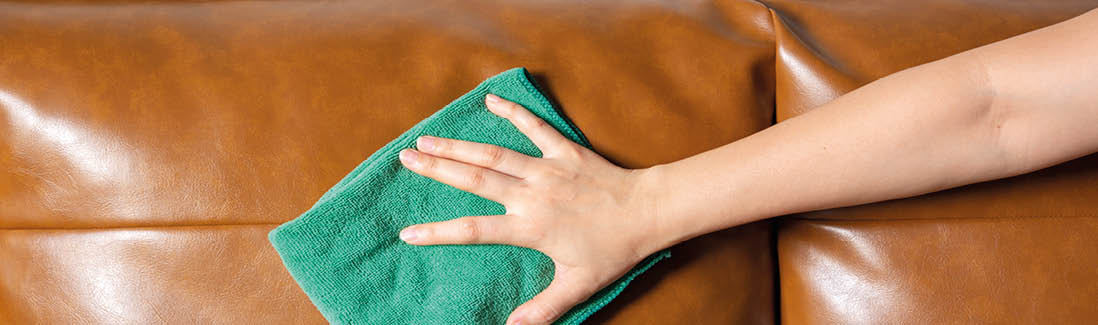 Woman hand cleaning leather sofa at home  Housekeeper or maid service concept