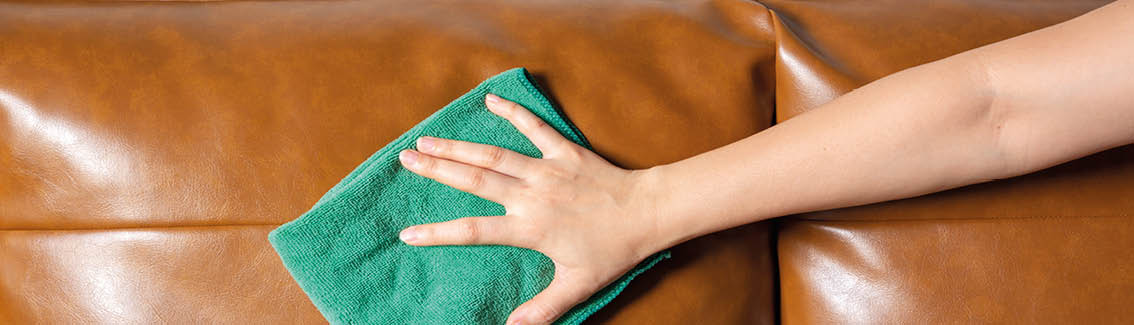 Woman hand cleaning leather sofa at home  Housekeeper or maid service concept