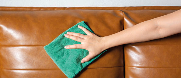 Woman hand cleaning leather sofa at home  Housekeeper or maid service concept